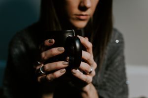 Sad woman drinking coffee - thinking about how she needs to see a therapist for counseling
